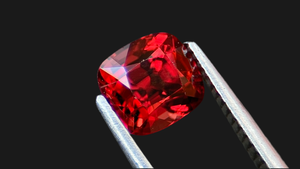 Intense crimson cushion-cut red spinel gemstone, sourced ethically from Mogok, Myanmar, set against a rich black background. Ideal for a distinctive, bespoke engagement ring.