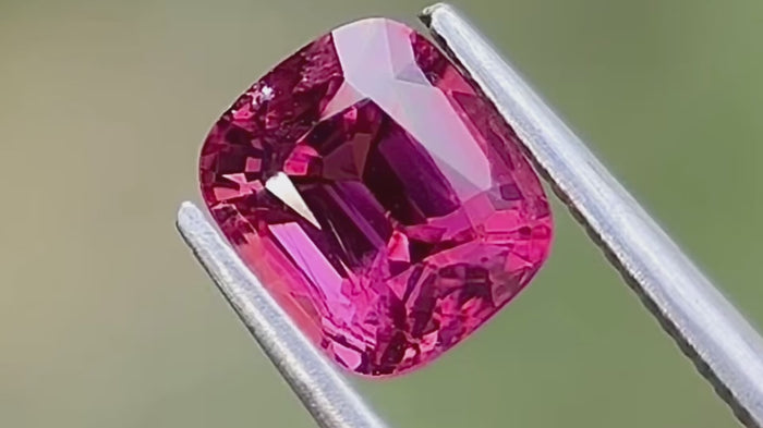 Intense pink natural spinel gemstone, cushion cut, under natural light, ideal for custom fine jewellery pieces. High-quality gemstone from Mogok, Myanmar. 