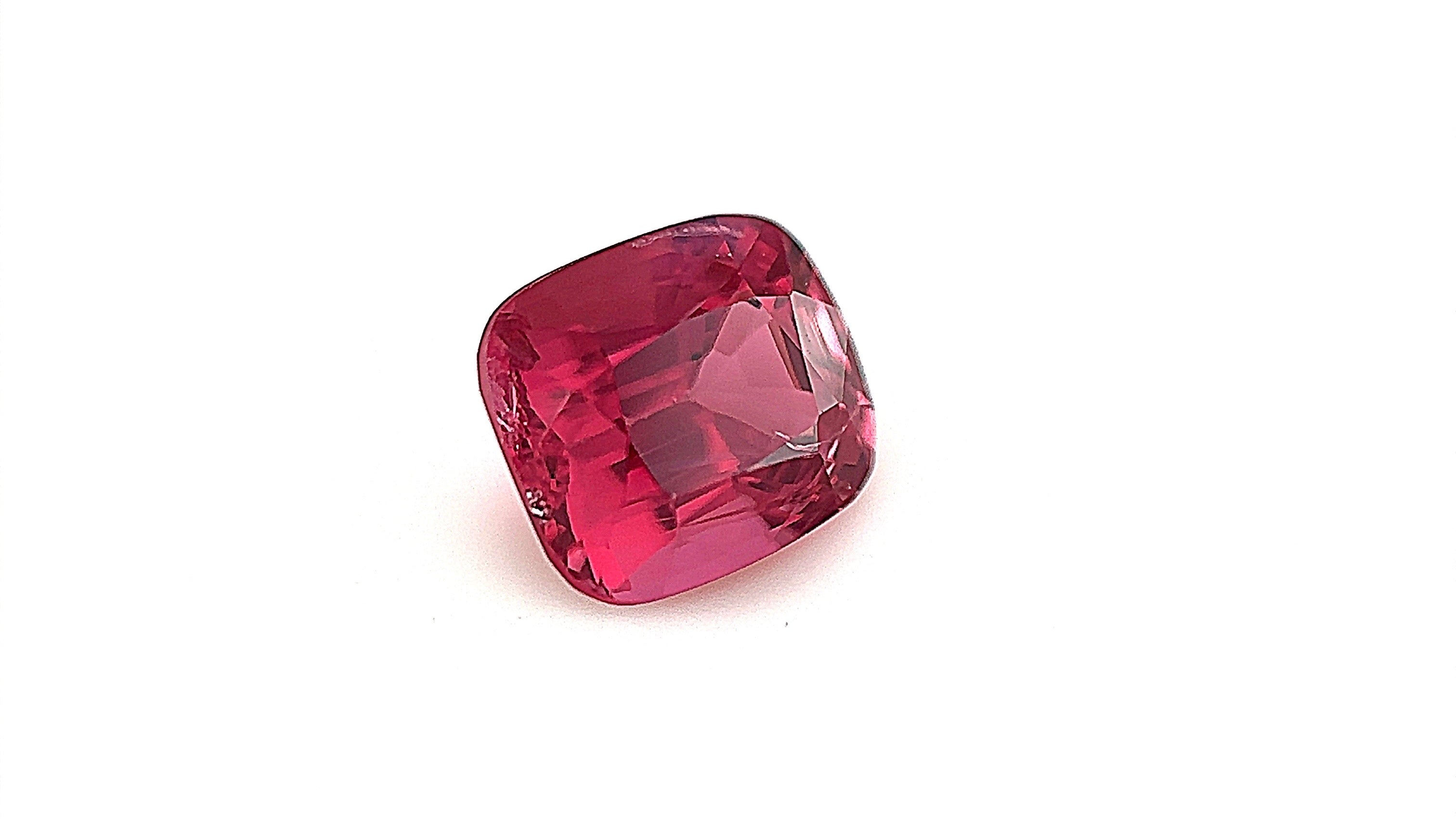 Intense pink natural spinel gemstone, cushion cut, under studio lightbox,ideal for custom fine jewellery pieces. High-quality gemstone from Mogok, Myanmar.